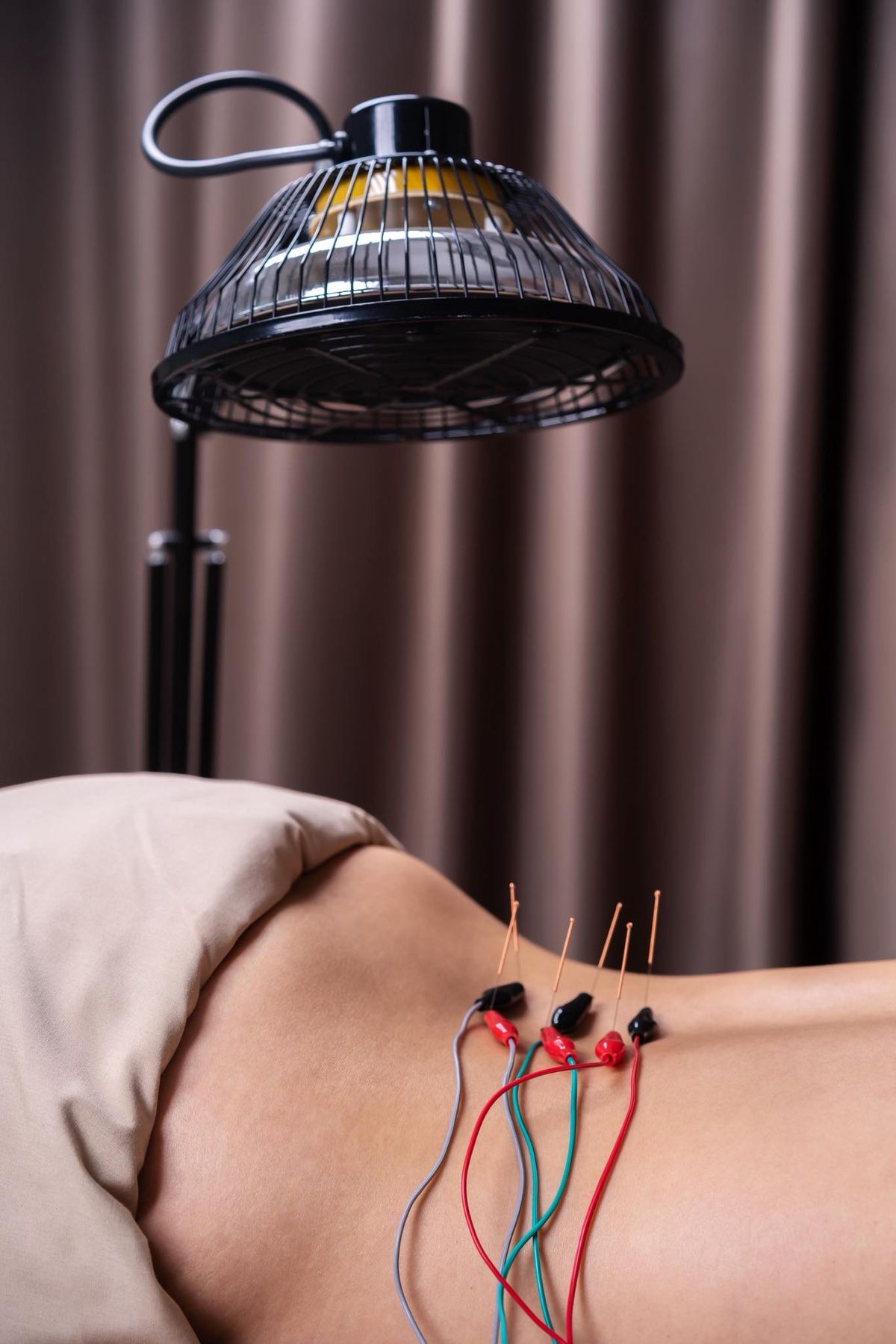 Electroacupuncture treatment for lower-back pain beneath a warming therapy lamp